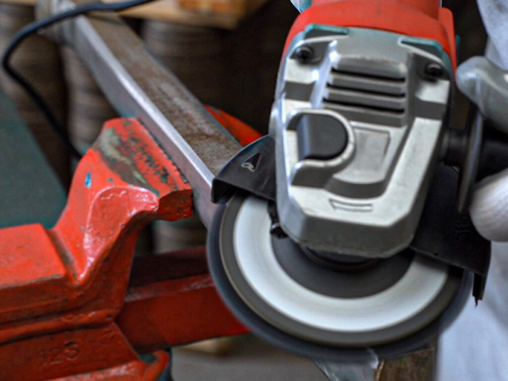 L'immagine di una smerigliatrice in azione con disco IMA Abrasivi commenta le applicazioni di Satinatura e Lucidatura